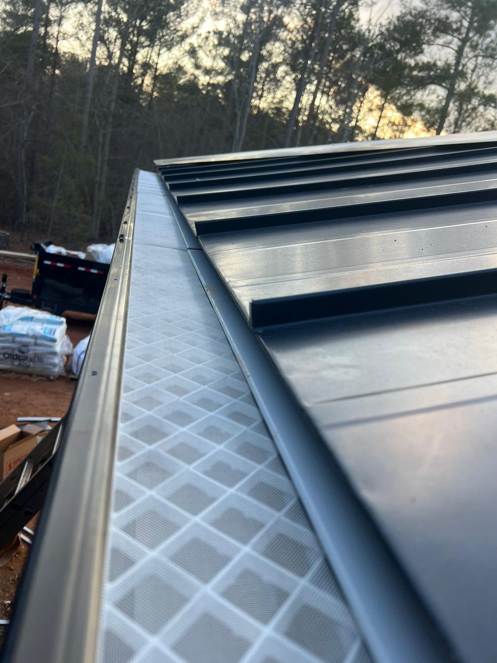 Detail of micromesh gutter guard installed alongside a dark standing-seam metal roof